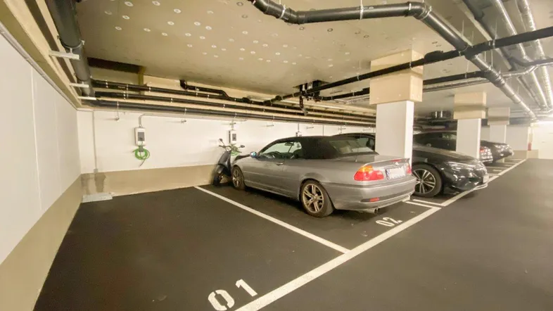 Tiefgarage mit mehreren Stellplätzen und einer Ladestation für Elektrofahrzeuge, unterirdisch gelegen.