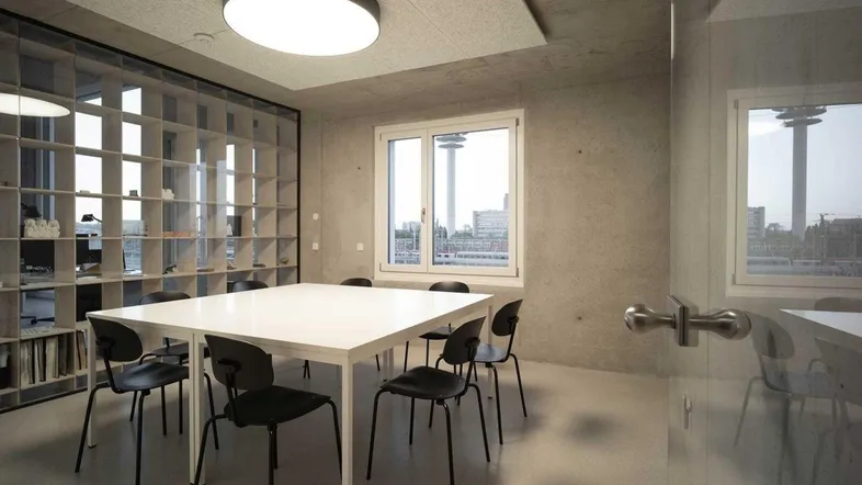 Moderner Besprechungsraum mit Sichtbetonwänden, großem Fenster und Blick auf den Stadtturm.