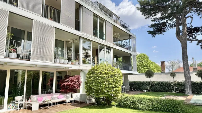 Moderne Wohnanlage mit großzügiger Gartenfläche und mehreren Balkonen, umgeben von viel Grün.
