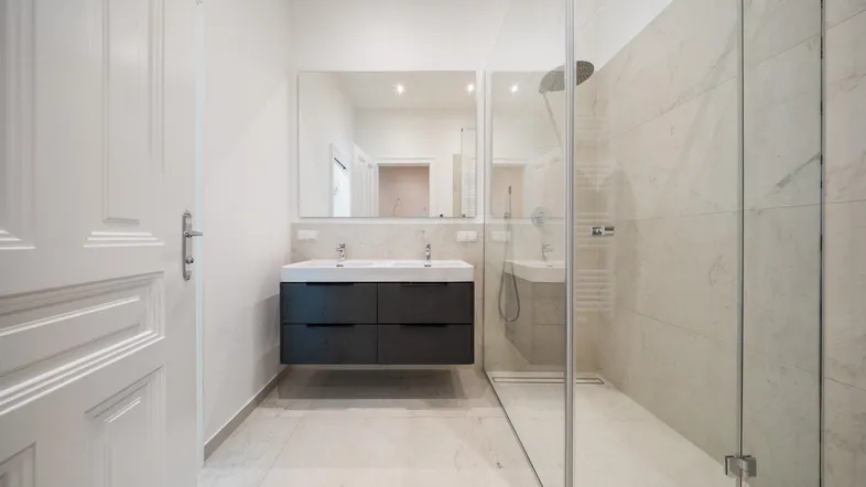 Modernes Badezimmer mit Doppelwaschbecken, großer begehbarer Dusche und hellen Fliesen.