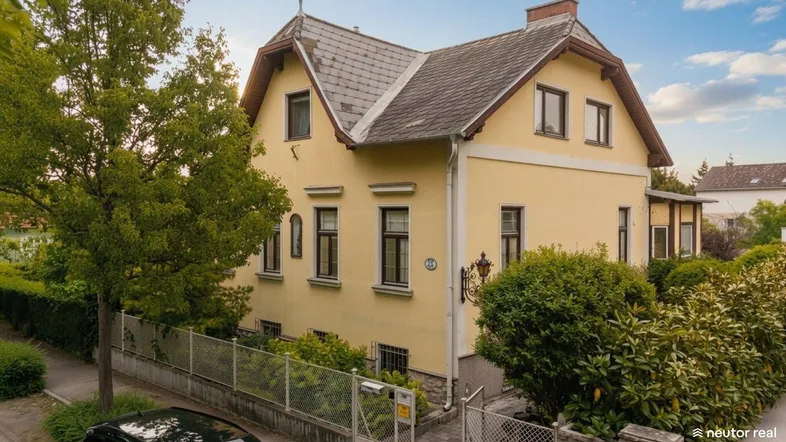 Charmantes Einfamilienhaus mit gelber Fassade und gepflegtem Vorgarten.