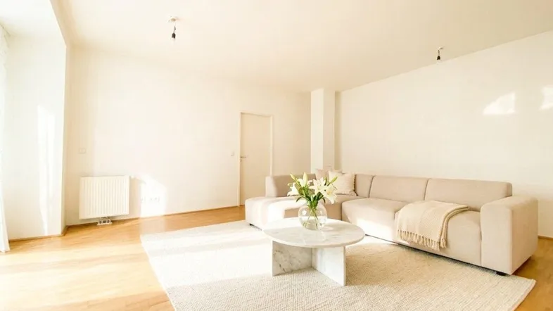 Helles Wohnzimmer mit beigem Sofa, modernem Couchtisch und Holzboden.