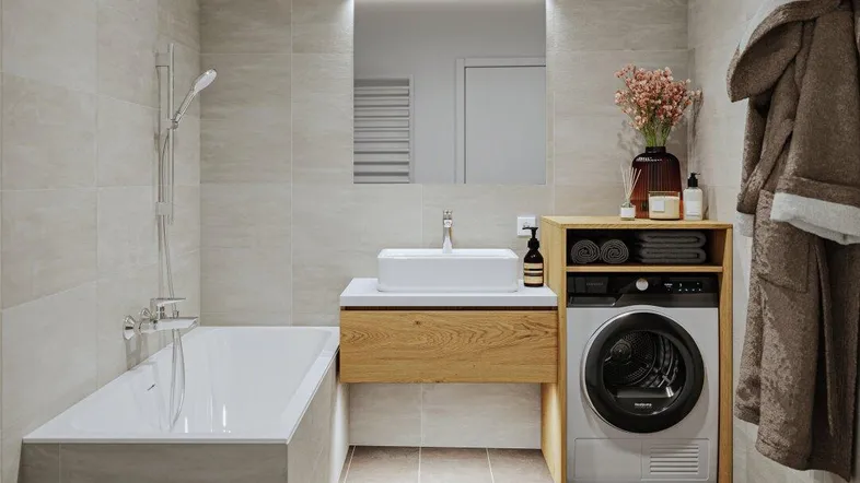 Modernes Badezimmer mit Badewanne, Waschbecken und integrierter Waschmaschine.