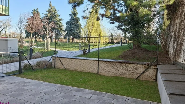 Kleiner privater Gartenbereich mit gepflasterter Terrasse und Zugang zu einer größeren Grünfläche.