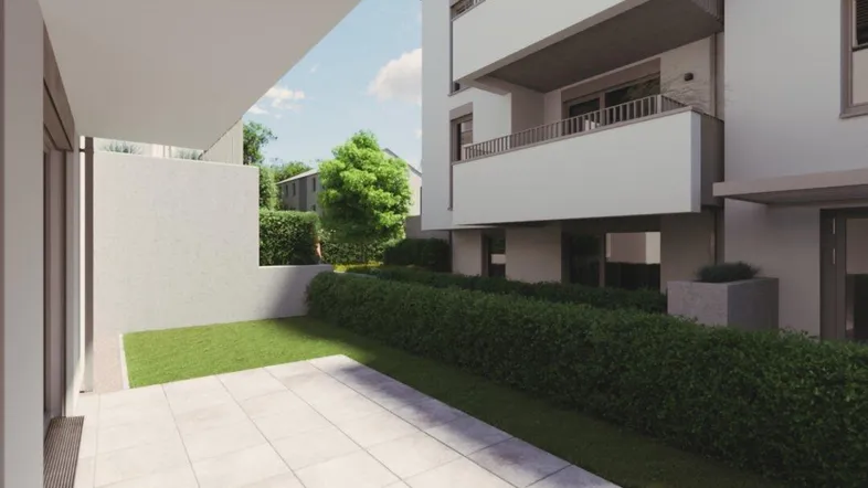 Moderne Terrasse mit Steinplatten und angrenzender Rasenfläche vor einem Neubau.