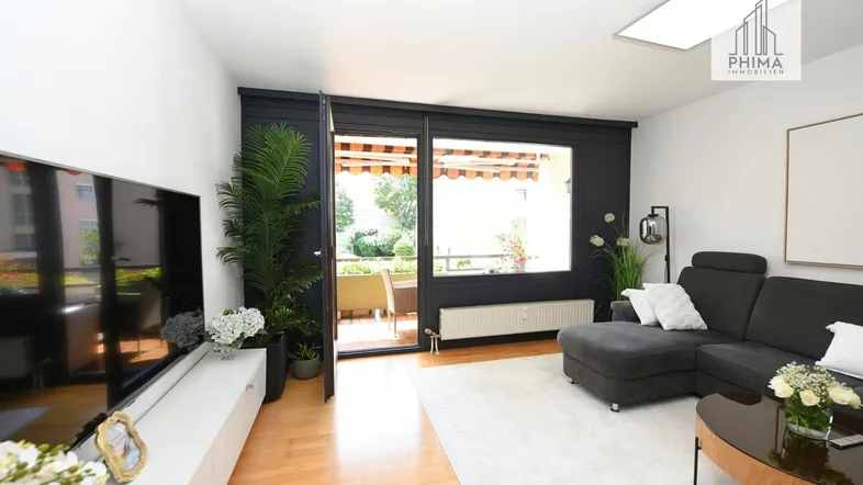 Helles Wohnzimmer mit modernem Sofa, Holzboden und Zugang zum Balkon.