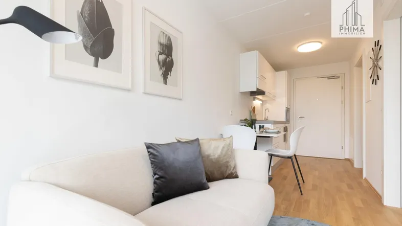 Heller offener Wohnbereich mit Sofa, Esstisch und integrierter Küchenzeile, ideal für modernes Wohnen.