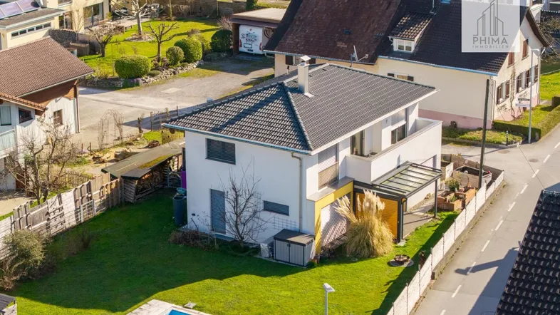 Luftaufnahme eines Einfamilienhauses mit Garten, Pool und umliegender Wohnbebauung.