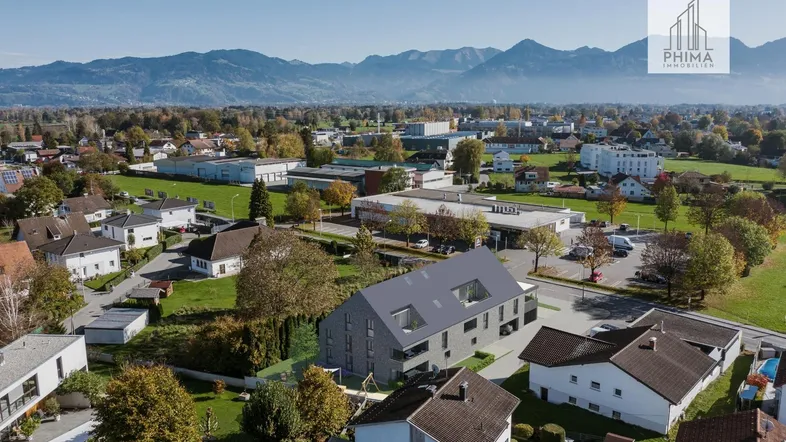 Luftaufnahme der Wohnanlage in ländlicher Umgebung mit Bergblick und umliegender Bebauung.
