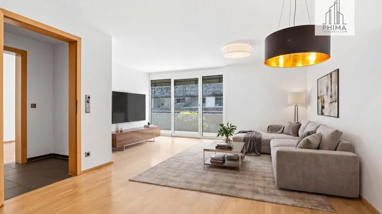 Modernes Wohnzimmer mit hellem Parkettboden, beigem Sofa und Zugang zum Balkon.