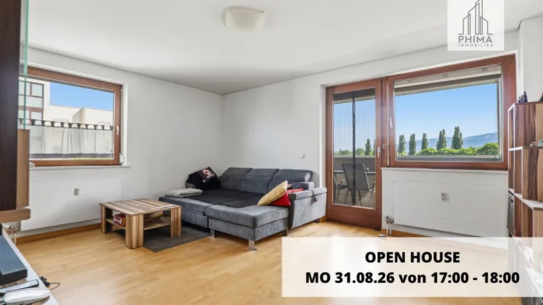 Helles Wohnzimmer mit Holzboden, großem Sofa und Zugang zum Balkon mit Weitblick.