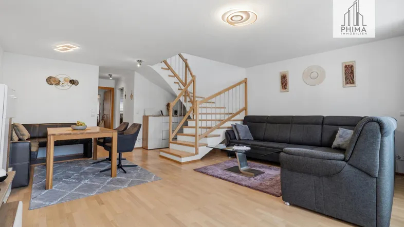 Geräumiger Wohn-Essbereich mit Holztreppe, Parkettboden und modernen Möbeln.