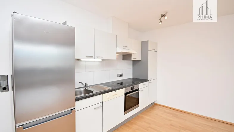 Moderne Einbauküche mit weißen Schränken, Edelstahlgeräten und hellem Holzfußboden.