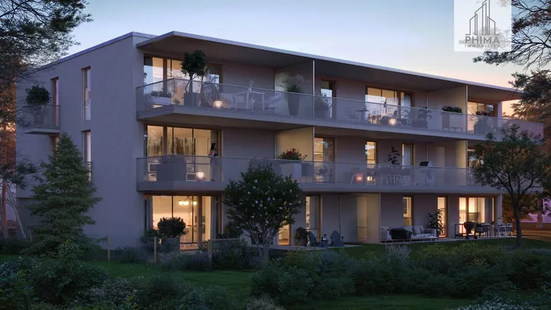 Moderne Wohnanlage mit großzügigen Balkonen und Terrassen, umgeben von viel Grün bei Abenddämmerung.