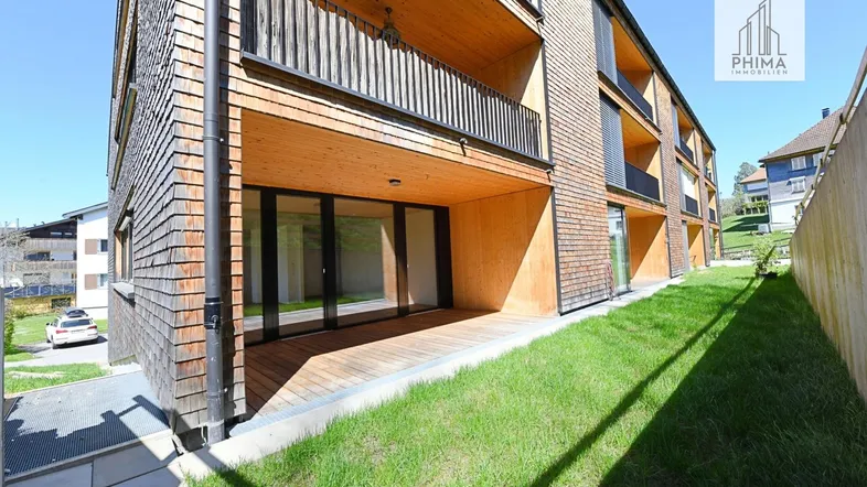 Moderne Holzfassade mit großzügiger Terrasse im Erdgeschoss und Balkonen in sonniger Lage.
