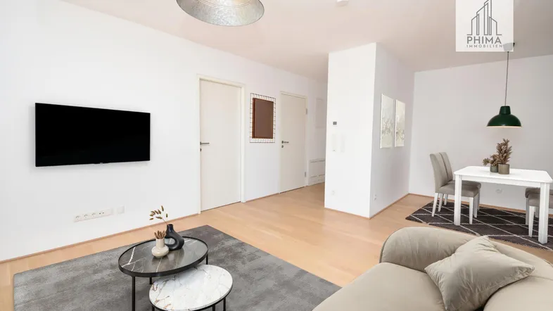 Heller offener Wohn- und Essbereich mit modernem Sofa, Esstisch und Holzboden.
