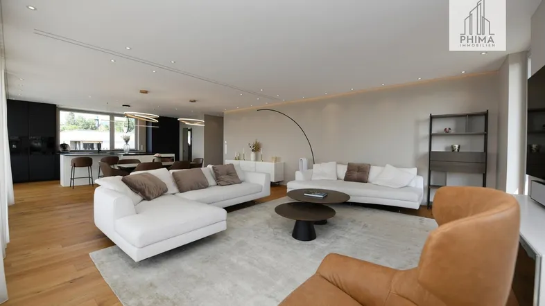 Helles, offenes Wohnzimmer mit modernen Sofas, Holzboden und Blick auf den Essbereich und die Küche.