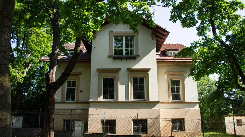 Klassisches Wohnhaus mit heller Fassade und traditioneller Architektur, umgeben von Bäumen.