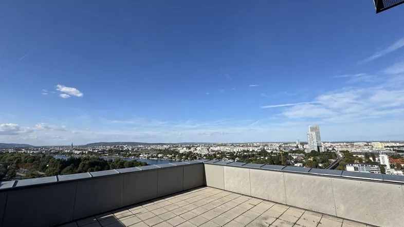 Große Dachterrasse mit weitem Blick über die Stadt und den Fluss unter blauem Himmel.