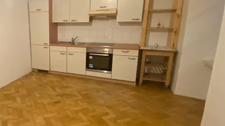 Kleine Einbauküche mit hellem Holzparkett und einfacher Ausstattung, inklusive Backofen.