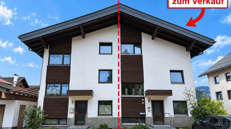 Doppelhaushälfte mit traditioneller Architektur und braunen Holzdetails unter blauem Himmel.