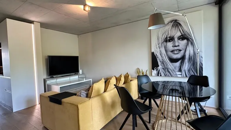 Moderner Wohn- und Essbereich mit gelbem Sofa, Holzboden und einer markanten Kunstwand.