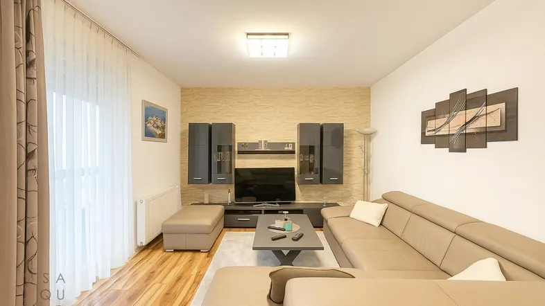 Modernes Wohnzimmer mit beiger Ledercouch, Holzboden und dekorativer Wandgestaltung.