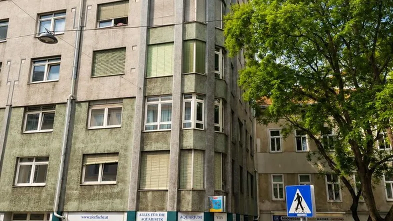Eckgebäude mit Geschäften im Erdgeschoss und Wohnungen darüber, an einer belebten Straße gelegen.