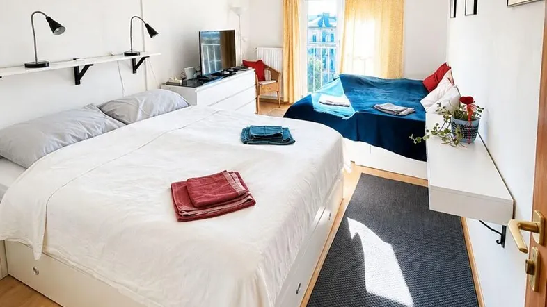 Helles Schlafzimmer mit zwei Betten, Holzboden und Klimaanlage für angenehmes Raumklima.