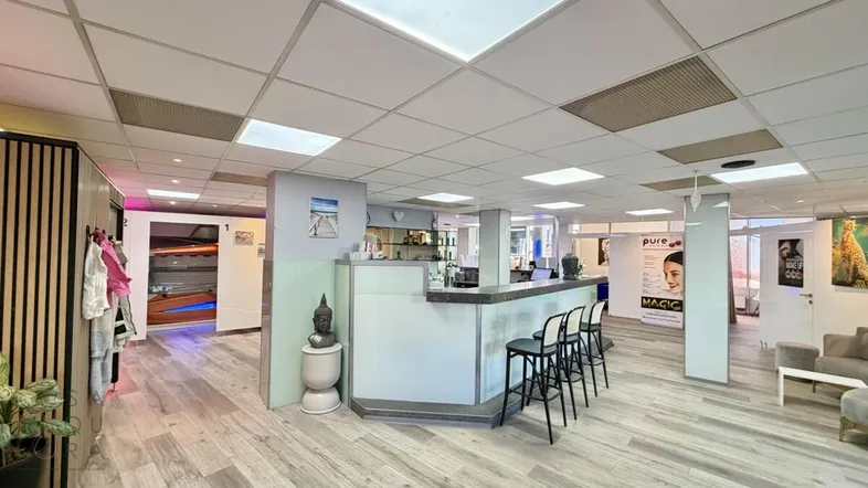 Empfangsbereich mit Bar, Sitzgelegenheiten und Blick auf die Solariumkabinen in einem modernen Ambiente.