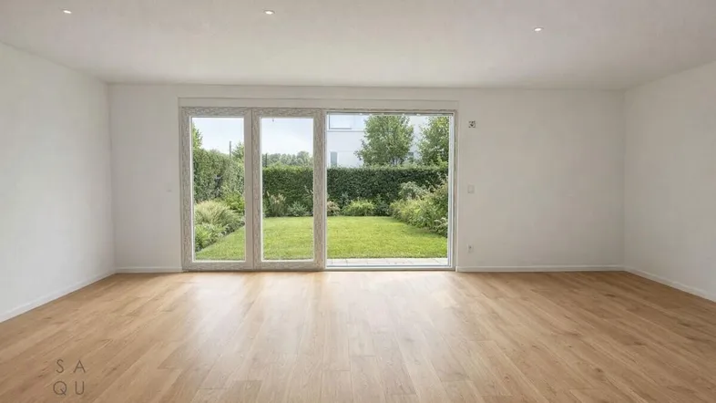 Helles Wohnzimmer mit Holzboden und großer Schiebetür zum grünen Gartenbereich.