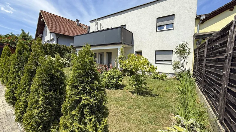 Modernes Haus mit gepflegtem Rasen und einer Reihe von Zypressen im Vorgarten.