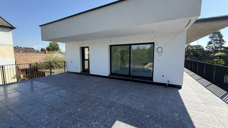 Große, geflieste Terrasse mit moderner Architektur und Blick ins Grüne, ideal für Entspannung im Freien.