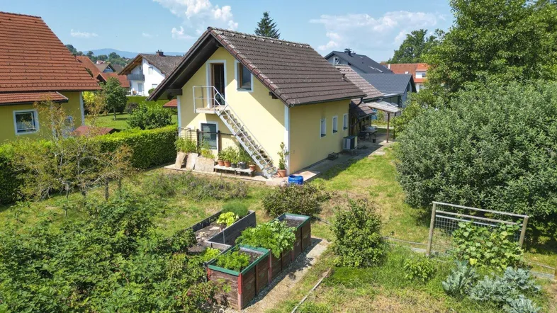 Luftaufnahme eines Einfamilienhauses mit großem Garten und Hochbeeten in ländlicher Umgebung.