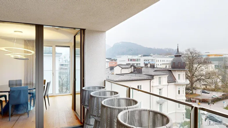 Geräumiger Balkon mit Sitzgelegenheiten und weitem Blick über die Stadt und Hügel.