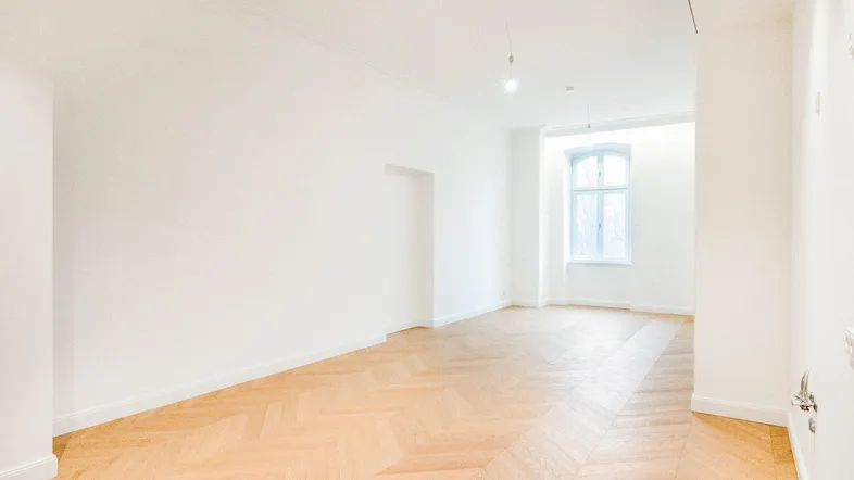 Helles, leeres Zimmer mit Fischgrätparkettboden und einem großen Fenster, bereit zur individuellen Gestaltung.