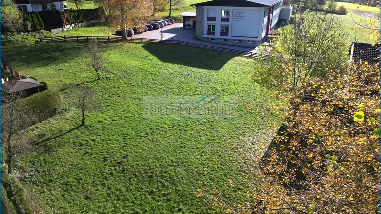 Luftaufnahme eines großen grünen Grundstücks mit umliegenden Gebäuden und Bäumen in sonniger Lage.
