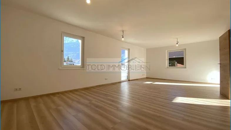 Heller, leerer Raum mit großen Fenstern und modernem Laminatboden, ideal für Wohn- oder Schlafzimmer.