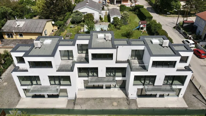 Moderne Wohnanlage mit Flachdächern und Balkonen, umgeben von einer grünen Wohngegend.