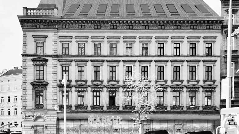 Historische Fassade eines Gebäudes mit modernisiertem Dachgeschoss und vielen Dachfenstern.