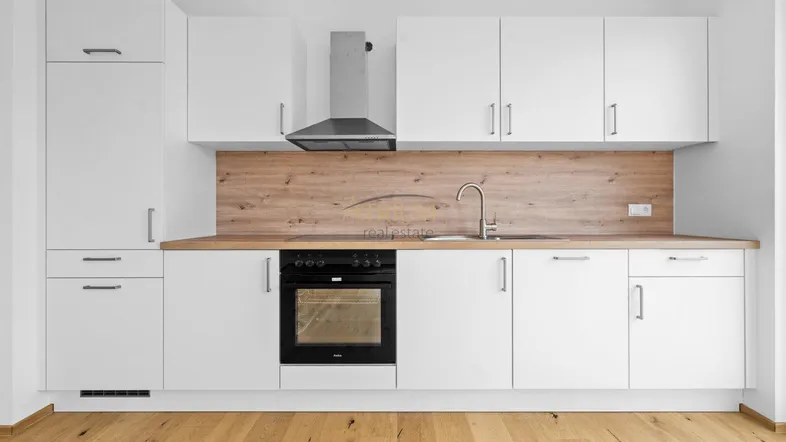 Moderne Einbauküche in Weiß mit Holzdetails, ausgestattet mit Backofen und Dunstabzugshaube.