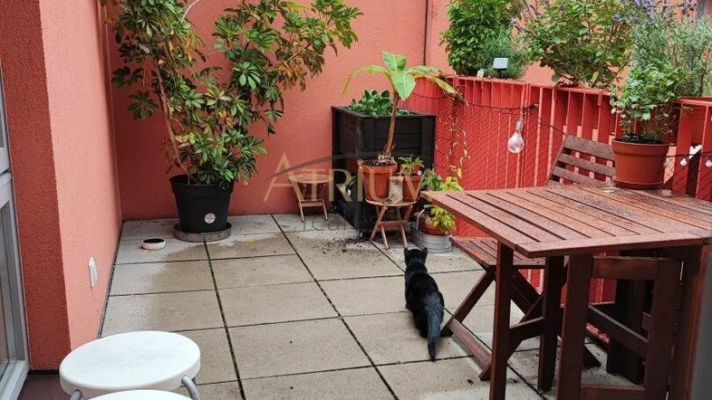 Geräumige Terrasse mit Fliesenboden, Pflanzen und einem Holztisch, ideal für entspannte Stunden im Freien.