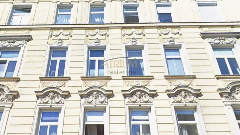 Historische Fassade eines Altbaus mit reich verzierten Fenstern und Stuckelementen.