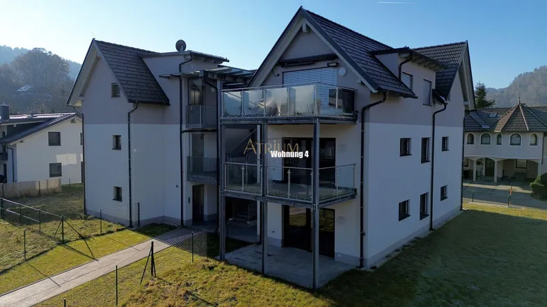 Modernes Mehrfamilienhaus mit mehreren Balkonen und gepflegter Außenanlage in grüner Umgebung.