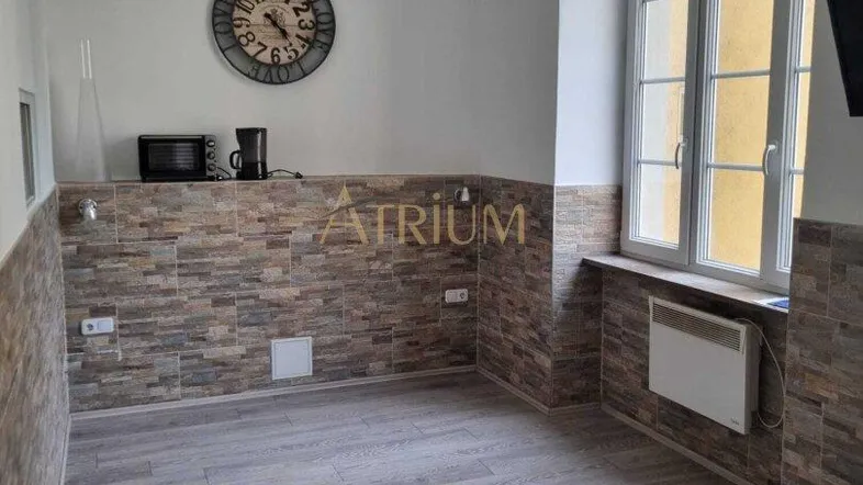 Helles Zimmer mit großen Fenstern, Holzboden und dekorativer Wandverkleidung, bereit für die Einrichtung.