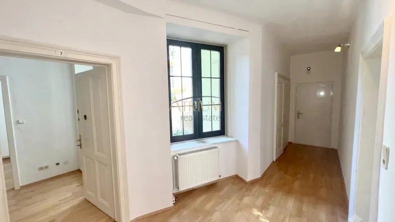 Heller Flur mit Holzboden, Fenster und Zugang zu weiteren Räumen.