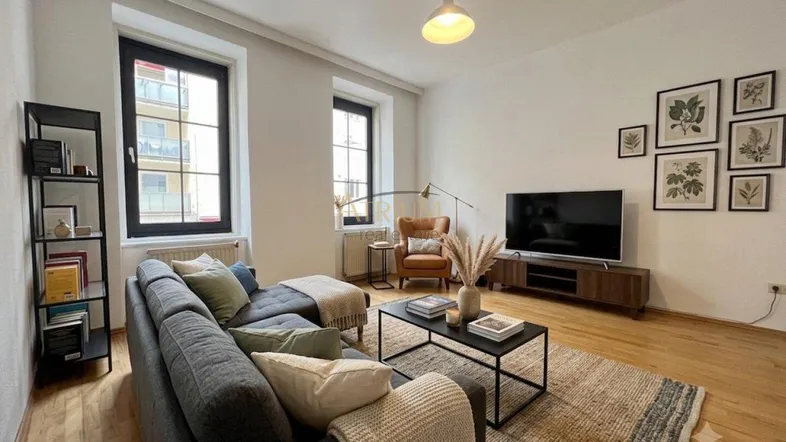 Modern eingerichtetes Wohnzimmer mit bequemer Couch, Holzboden und Blick auf die Stadt.