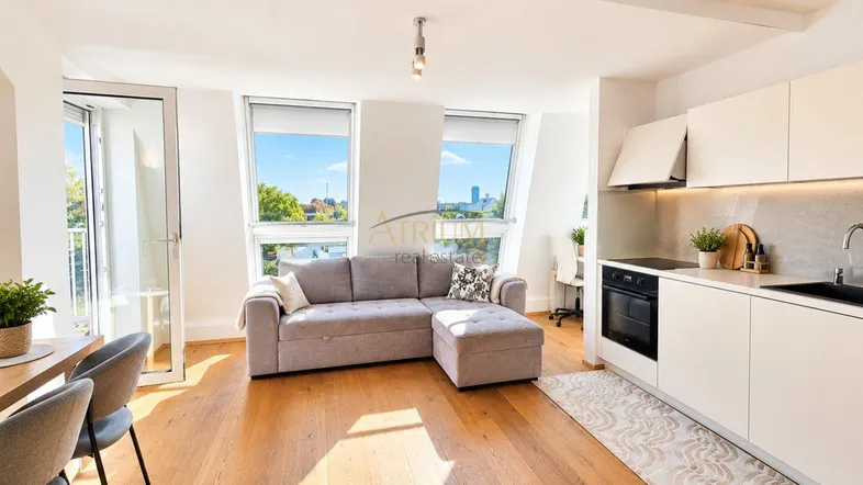 Helles, offenes Wohnzimmer mit integrierter Küche, Holzboden und Zugang zu einem kleinen Balkon.