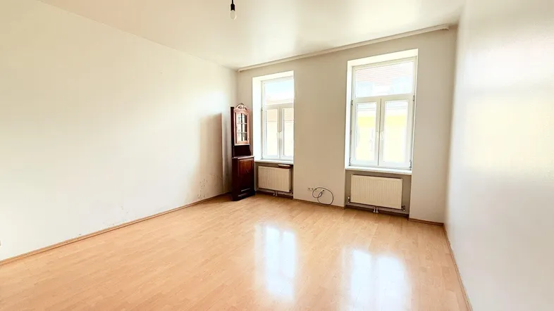 Heller Raum mit Laminatboden, weißen Wänden und zwei großen Fenstern, ideal als Wohn- oder Schlafzimmer.