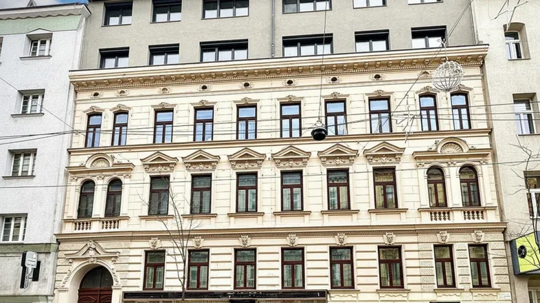 Historische Fassade eines Altbaus mit modernem Dachgeschossausbau und großen Fenstern.